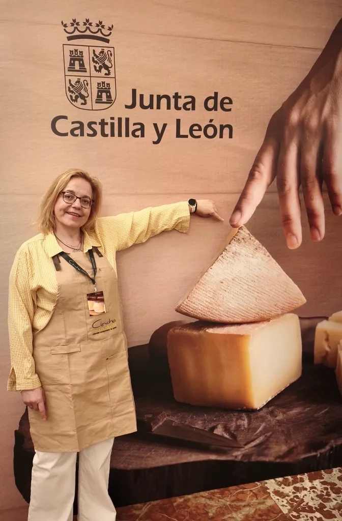 Ruth Lozano at the Junta de Castilla y León stand during the Cincho competition, pointing to a large wedge of cheese.
